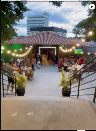 Área externa do Bharzin à noite com varal de luzes e mesas cheias